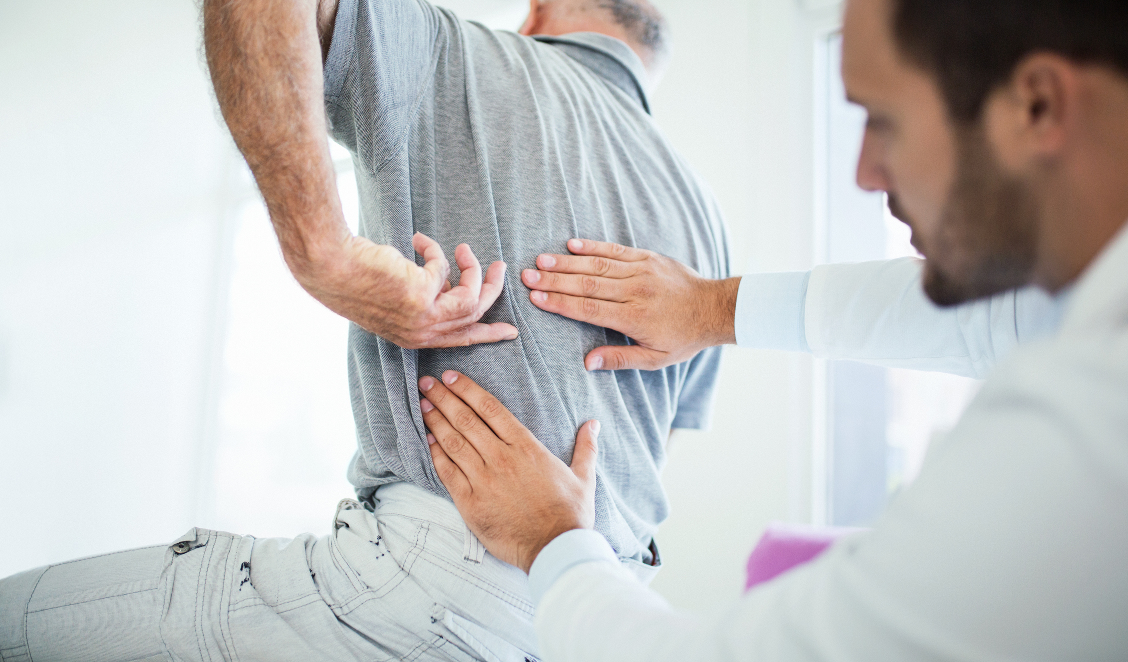 Chiropractor evaluating lower back pain during car accident pain management treatment in Florida