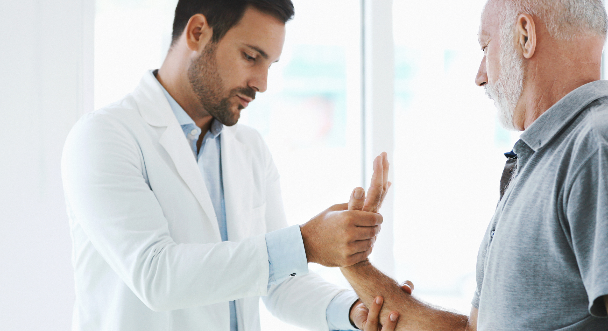 Pain management doctor examining a patient’s wrist and joint pain during a post-accident evaluation in Fort Myers, Florida