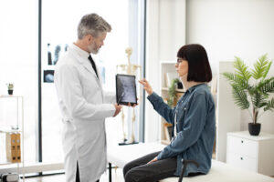 Doctor reviewing an X-ray with a patient wearing a neck brace during an auto accident injury evaluation.