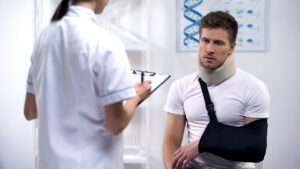 Injured man wearing a neck brace and arm sling during a medical evaluation after an auto accident