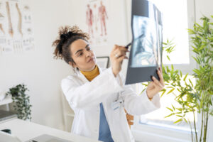 Healthcare provider reviewing spinal X-ray images in a bright medical office, evaluating possible neck or back injuries and discussing diagnostic findings.