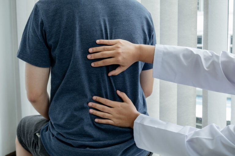 Healthcare provider assessing a patient’s back during a post-accident back pain evaluation.