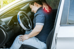 Driver experiencing neck pain while seated in a car after an accident, illustrating delayed injury symptoms.
