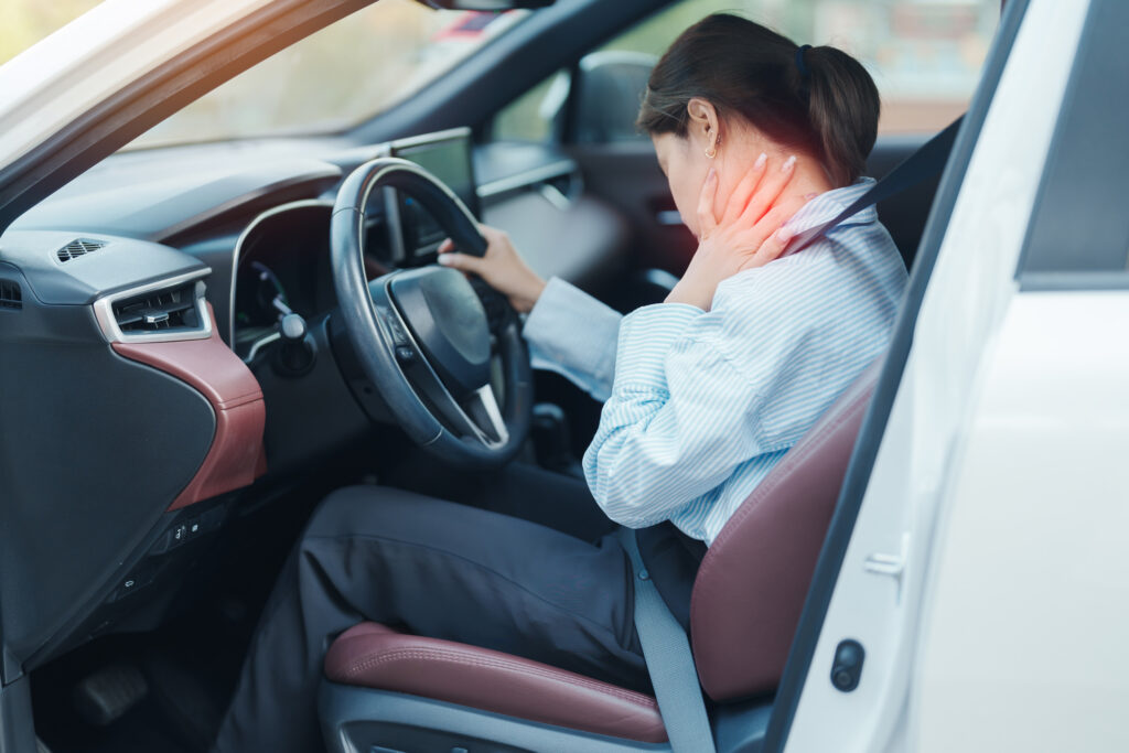 Woman holding her neck in pain while seated in a car, illustrating whiplash after a car accident in Clearwater.