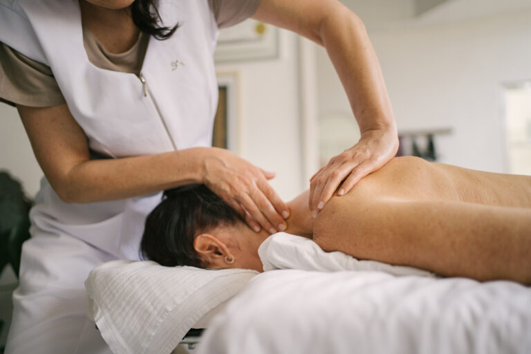 Healthcare provider applying hands-on therapy to a patient’s neck and upper back during treatment.